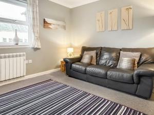 a living room with a black leather couch at Brada View in Bamburgh