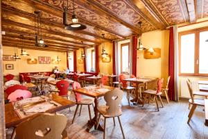a restaurant with wooden tables and chairs and windows at The Originals Boutique, Hôtel La Ferme du Pape, Eguisheim in Eguisheim