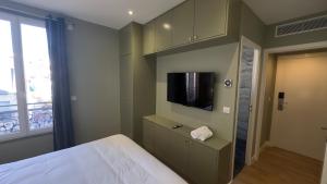 a bedroom with a bed and a flat screen tv at Alma Hotel in Courbevoie