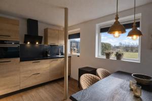 a kitchen with a table and a dining room at Ballumerhoeve Fleuri lodge in Ballum
