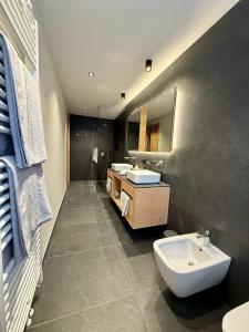 a bathroom with two sinks and a toilet and a mirror at Appartamento Rododendro in Andalo +57 photos