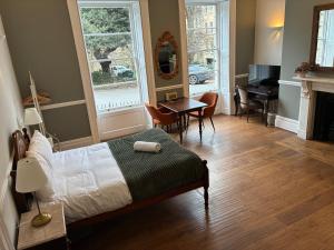 a bedroom with a bed and a desk and a piano at 3 Berkeley Square Guesthouse in Bristol +54 photos