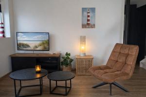 a living room with a chair and a table and a television at Ballumerhoeve Fleuri lodge in Ballum