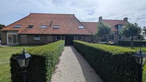 a house with a hedge fence and a driveway at Ballumerhoeve Fleuri lodge in Ballum
