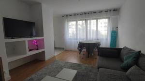 a living room with a couch and a table at Charming Bagneux Nest in Bagneux