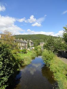 a river in a town with houses and trees at Peebles Cottage Apartment with River View and Bike Store in Peebles
