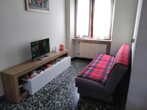 a living room with a couch and a tv and a chair at La porta sul Viale in Cuneo
