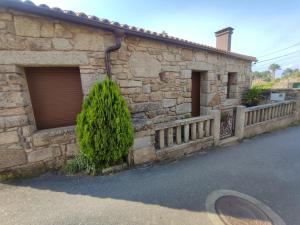a stone building with two garage doors and a tree at O Iniño casita rural costera in O Grove