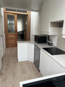 a kitchen with white cabinets and a black appliance at Holiday house with private jaccuzi - Leuven city center in Leuven