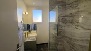 a bathroom with a glass shower and a sink at Alma Hotel in Courbevoie