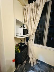 a window with a curtain and a microwave in a room at Velouria Homestay in Guwahati +11 photos