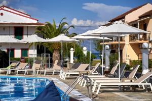 a pool with chairs and umbrellas next to a building at Fardini Resorts in Kavos