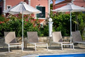 a group of chairs and umbrellas next to a pool at Fardini Resorts in Kavos
