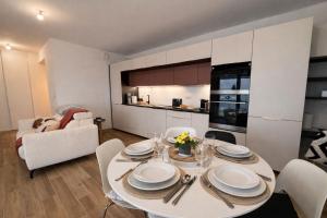 a dining room with a white table and a kitchen at L'Instant Cocoon central-parking-4prs in Bourg-en-Bresse