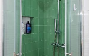 a green tiled shower with a bottle of shampoo at Casa João de Quintal in Elvas