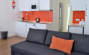 a gray couch with an orange pillow in a kitchen at Casa João de Quintal in Elvas