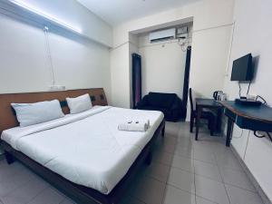 a bedroom with a bed and a desk and a computer at HOTEL IHAM PARADISE - Near Mangalore Central Railway Station - Pets Not Allowed in Mangalore
