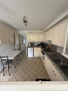 a kitchen with white cabinets and a table in it at Maison 4 à 8 personnes in Faches-Thumesnil +3 photos