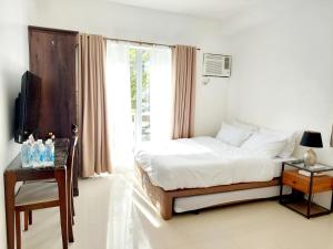 a white bedroom with a bed and a window at Affordable Stylish & Cozy Walk Up Condo in Minglanilla