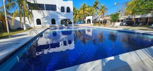 a swimming pool in front of a white building with blue tiles at Habitación en villa Costa del sol in Los Blancos
