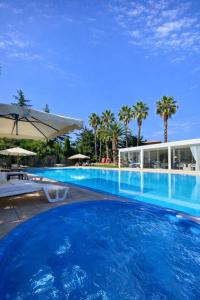 a large swimming pool with palm trees and a building at Villa Adriana - Private Pool Villa in Puglia in Andria