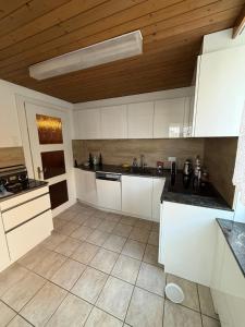 a kitchen with white cabinets and a wooden ceiling at Urlaub am Bodensee in Staad - einmalige Seesicht in Staad