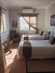 a bedroom with two beds and a chair at Table Mountain Guesthouse in Malmesbury +6 photos