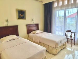zwei Betten in einem Hotelzimmer mit Fenster in der Unterkunft Hotel Caredek in Solok