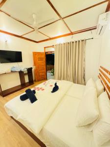 a large white bed with two black hats on it at Sevenseas Seaview Maldives in Feridhoo