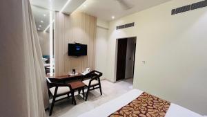 ein Zimmer mit Tisch, Stühlen und Fernseher in der Unterkunft Hotel The Marque Mathura in Mathura