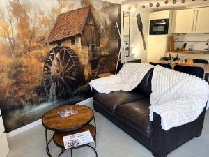 a living room with a couch and a mill mural at Le Ptit studio du vieux moulin in Rochefort