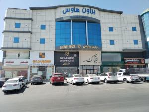 a large building with cars parked in a parking lot at براون هاوس للشقق المخدومة in Quai