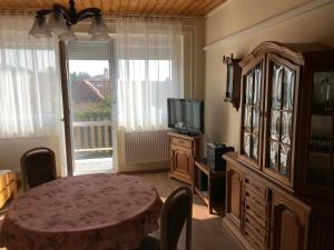a living room with a table and a tv and a dining room at PBJ Apartman in Pilisborosjenő