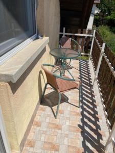a glass table and two chairs on a patio at PBJ Apartman in Pilisborosjenő +1 photo