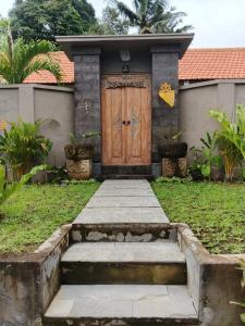 a wooden door with steps in front of a house at Umakami Pertiwi Villas in Ubud