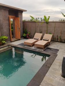 a swimming pool with two chairs next to a house at Umakami Pertiwi Villas in Ubud