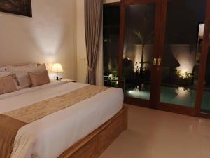 a bedroom with a bed and a large window at Umakami Pertiwi Villas in Ubud