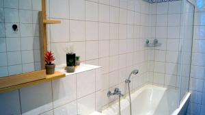 a white tiled bathroom with a tub and a sink at Ferienwohnung Hanna in Bitterfeld +74 photos