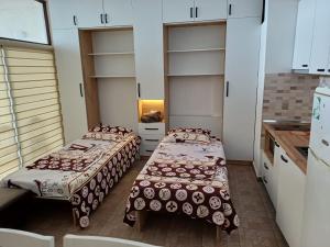 two beds in a room with white cabinets at Flat Ergli in Velipojë