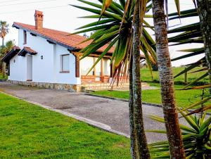 a white house with a palm tree in front of it at El Pinar de Arna in Castanedo