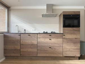 a kitchen with wooden cabinets and a sink at Wellness huisje Sonne Oase in Lanaken