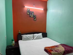 a bedroom with a white bed with an orange wall at Hotel Baba Dx in Samastīpur