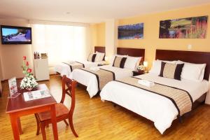 a hotel room with three beds and a table at Hotel Xilon Resort Pasto in Pasto