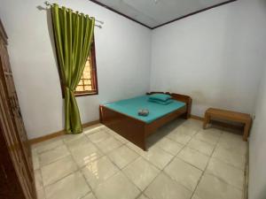 a room with a blue bed and a window at Ipoeng Rest Bed & Breakfast in Gorontalo