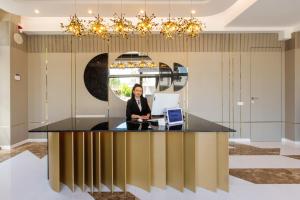 a woman sitting at a desk in an office with a laptop at Onal Boutique Hotelier in Mamaia