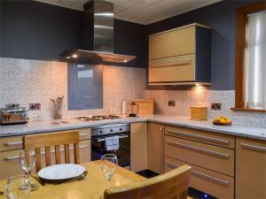 a kitchen with a wooden table with chairs and a sink at Bankhead Farm Cottage in Donibristle