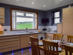 a kitchen with a table and a sink and a window at Bankhead Farm Cottage in Donibristle
