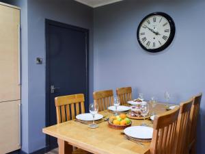 a dining room table with a clock on the wall at Bankhead Farm Cottage in Donibristle