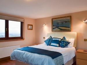 a bedroom with a large bed with blue pillows at Bankhead Farm Cottage in Donibristle