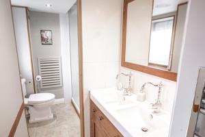 a white bathroom with a toilet and a sink at Waterfront Boathouse - Drift Cottage in Plymouth +24 photos